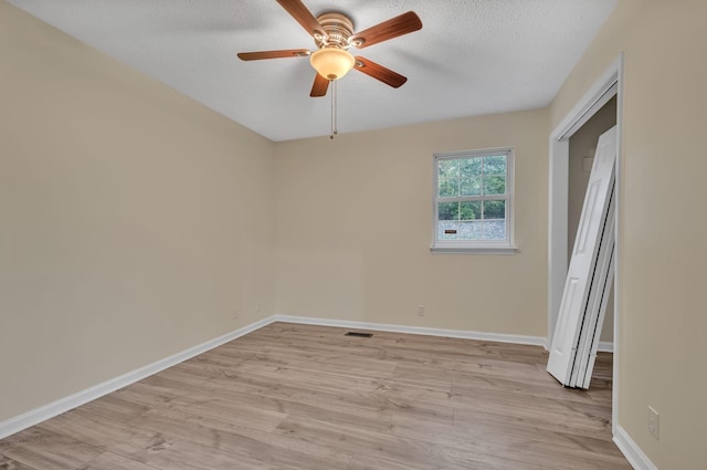 spare room with ceiling fan, a textured ceiling, and light hardwood / wood-style flooring