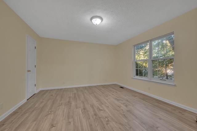 spare room featuring a textured ceiling and light hardwood / wood-style floors