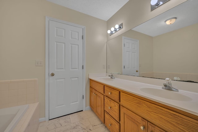 bathroom with vanity, a relaxing tiled tub, and a textured ceiling