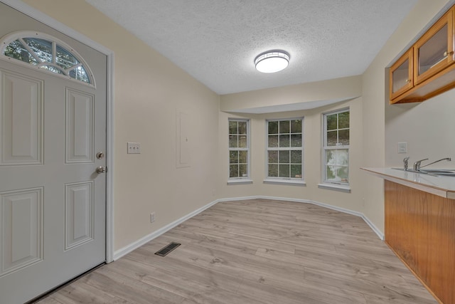 unfurnished dining area featuring a textured ceiling, light hardwood / wood-style floors, and sink