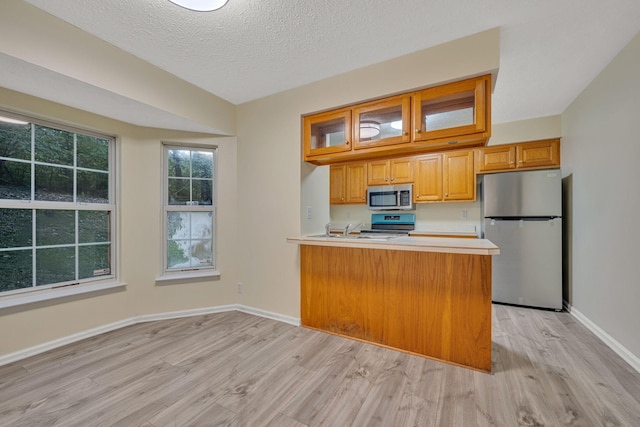 kitchen with kitchen peninsula, stainless steel appliances, a textured ceiling, and light wood-type flooring