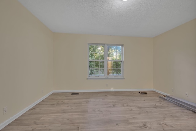 spare room with light hardwood / wood-style flooring and a textured ceiling