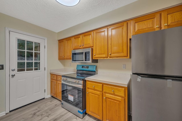 kitchen featuring light hardwood / wood-style floors, a textured ceiling, and appliances with stainless steel finishes