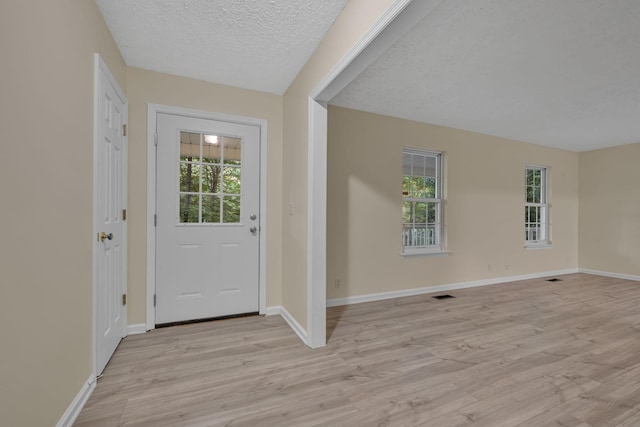 foyer entrance featuring plenty of natural light, light hardwood / wood-style floors, and a textured ceiling