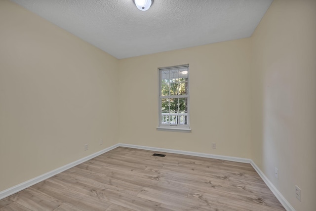 empty room featuring light wood-type flooring and a textured ceiling