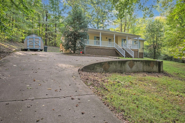 view of front of property featuring covered porch and a shed