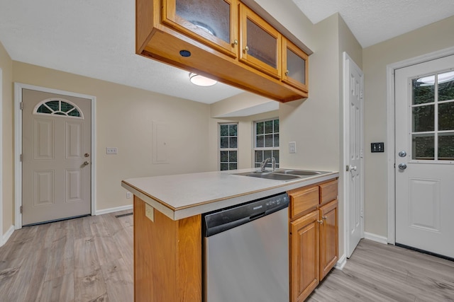 kitchen featuring kitchen peninsula, stainless steel dishwasher, a textured ceiling, sink, and light hardwood / wood-style floors