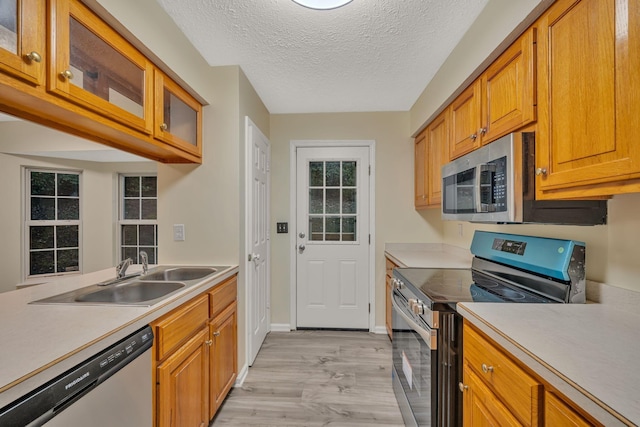 kitchen featuring a textured ceiling, stainless steel appliances, light hardwood / wood-style floors, and sink