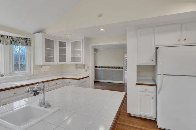 kitchen featuring white cabinetry, sink, white refrigerator, wood-type flooring, and lofted ceiling