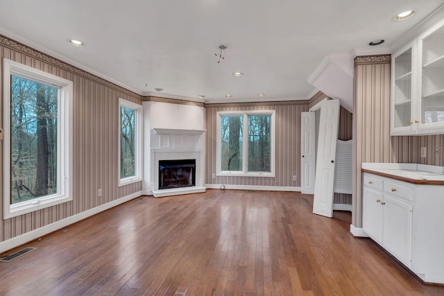 unfurnished living room featuring wood-type flooring and ornamental molding