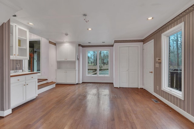 unfurnished living room with sink, ornamental molding, and light wood-type flooring