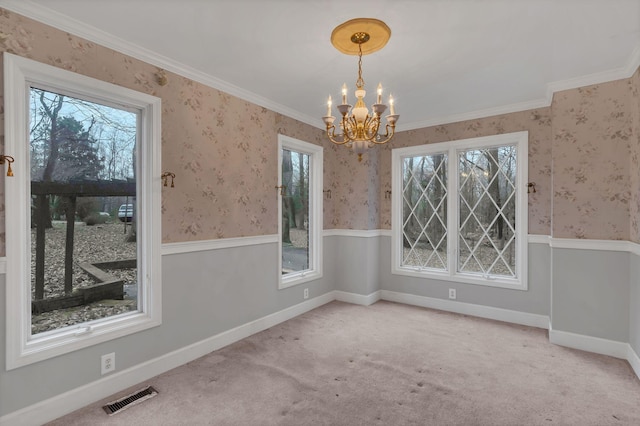 unfurnished dining area with carpet flooring, ornamental molding, a healthy amount of sunlight, and an inviting chandelier