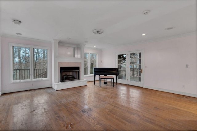 unfurnished living room with crown molding, a healthy amount of sunlight, and hardwood / wood-style flooring