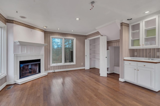 unfurnished living room with sink, light wood-type flooring, and crown molding