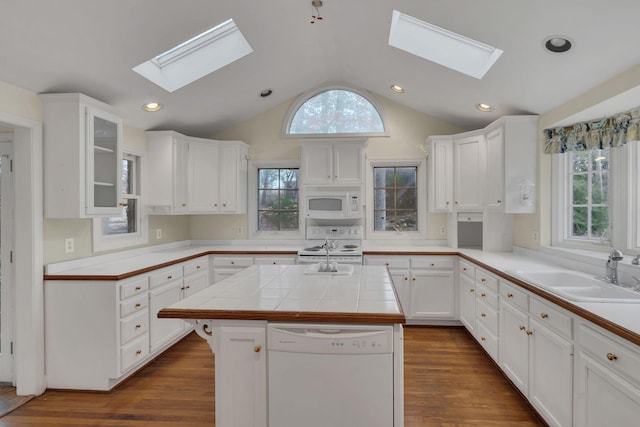 kitchen featuring tile counters, white cabinetry, a center island, and white appliances