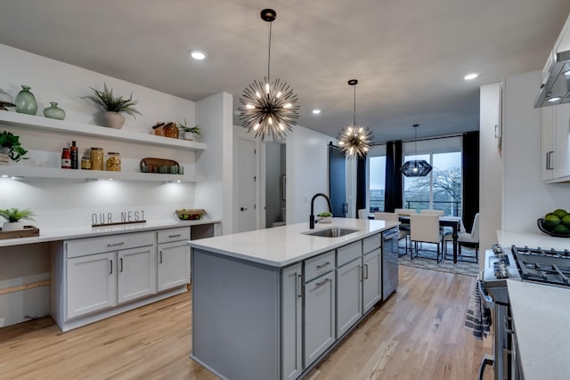 kitchen with pendant lighting, light wood-type flooring, exhaust hood, and sink