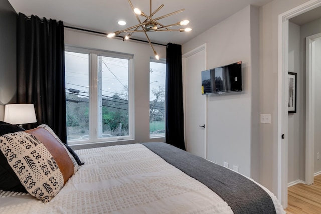 bedroom with light hardwood / wood-style flooring and a notable chandelier