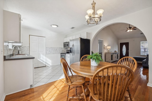 dining room featuring sink, ceiling fan with notable chandelier, and light hardwood / wood-style flooring