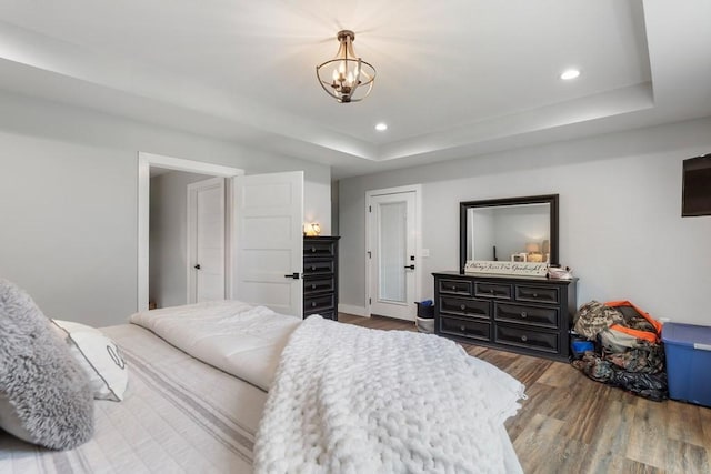 bedroom featuring dark hardwood / wood-style flooring, a raised ceiling, and a notable chandelier