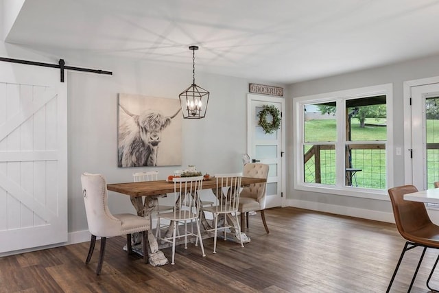 dining area featuring a notable chandelier, a barn door, and dark hardwood / wood-style flooring