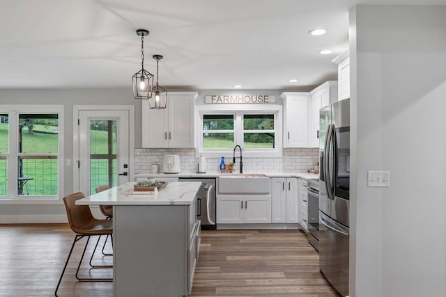 kitchen featuring a breakfast bar, white cabinets, sink, appliances with stainless steel finishes, and a kitchen island