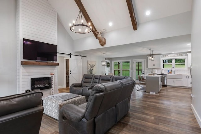 living room featuring high vaulted ceiling, dark hardwood / wood-style floors, a barn door, a fireplace, and beam ceiling