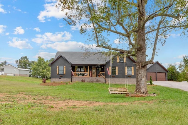 view of front of home featuring covered porch, a garage, and a front lawn