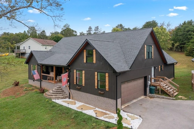 view of front of home with covered porch, a garage, and a front yard