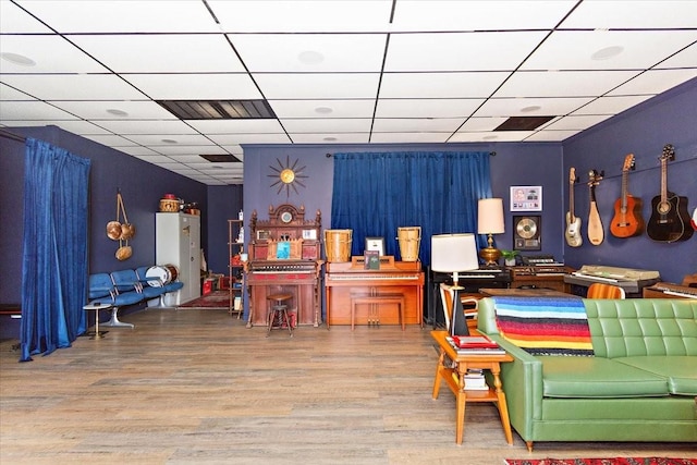 interior space with a drop ceiling and hardwood / wood-style flooring