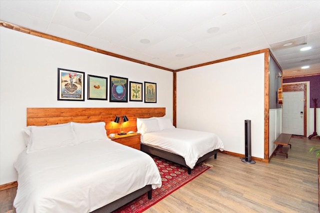 bedroom with ornamental molding and light wood-type flooring