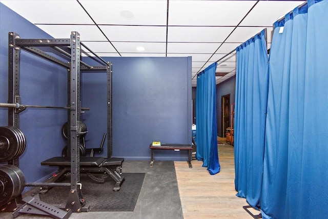 workout area with a paneled ceiling and wood-type flooring