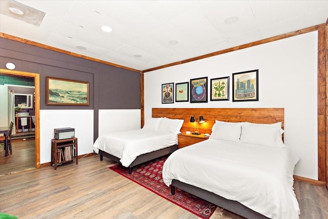 bedroom with hardwood / wood-style flooring, ornamental molding, and wood walls