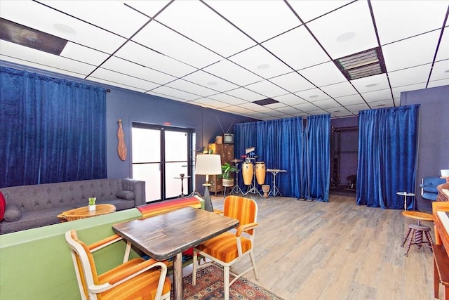 dining area featuring a drop ceiling and hardwood / wood-style flooring