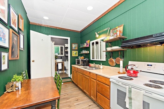 kitchen with sink, wooden walls, white electric range oven, light hardwood / wood-style floors, and extractor fan