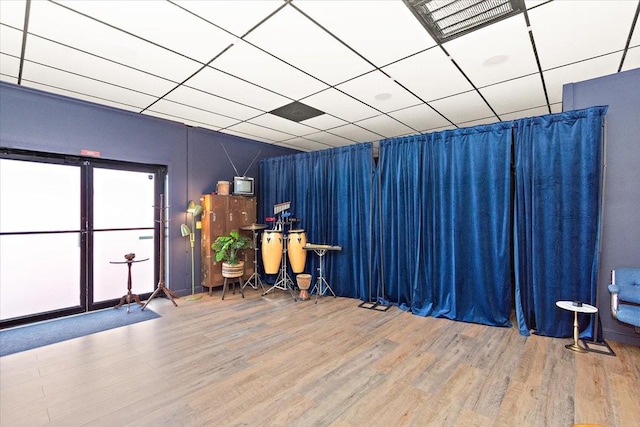 misc room featuring wood-type flooring and a drop ceiling