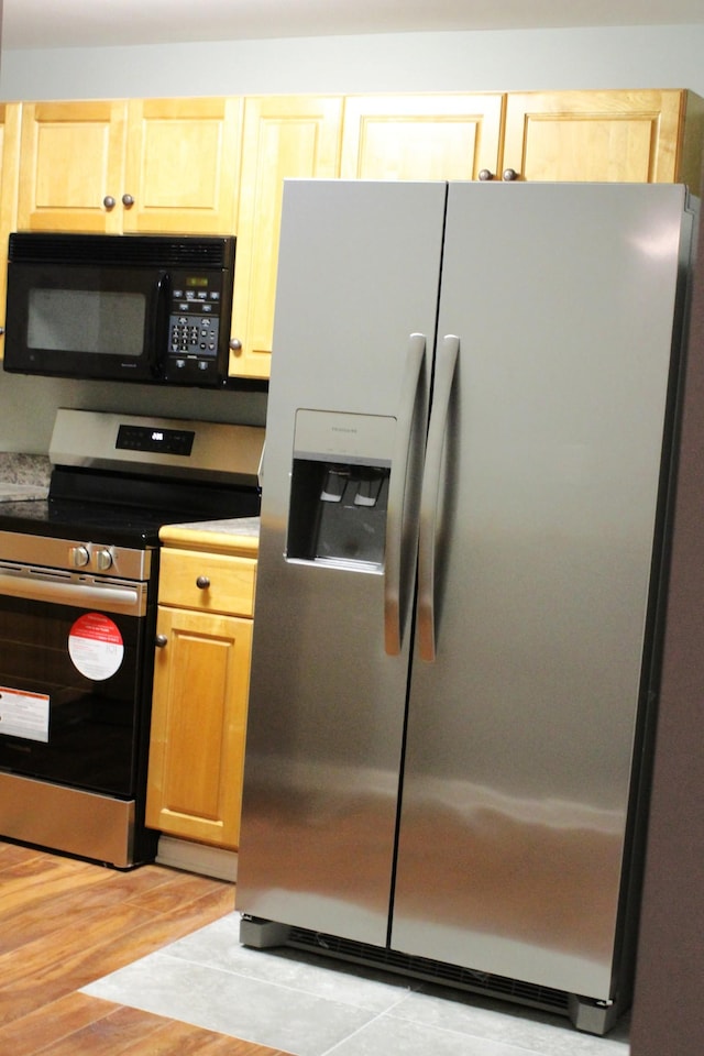 kitchen with light hardwood / wood-style floors, light brown cabinetry, and appliances with stainless steel finishes