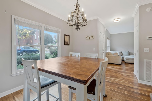 dining area with a healthy amount of sunlight, crown molding, and light hardwood / wood-style flooring