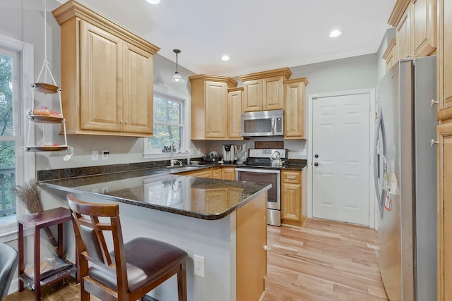 kitchen with kitchen peninsula, a healthy amount of sunlight, decorative light fixtures, and appliances with stainless steel finishes