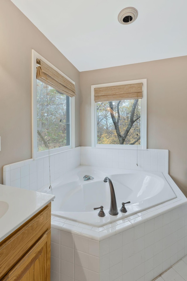 bathroom with tile patterned flooring, vanity, and tiled bath