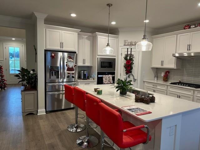 kitchen with hanging light fixtures, a kitchen breakfast bar, an island with sink, white cabinets, and black appliances