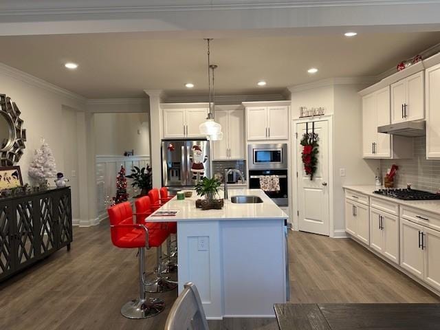 kitchen with sink, stainless steel appliances, tasteful backsplash, an island with sink, and decorative light fixtures