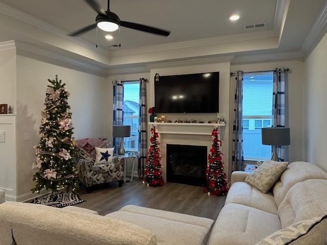 living room featuring ceiling fan, dark wood-type flooring, a wealth of natural light, and a tray ceiling