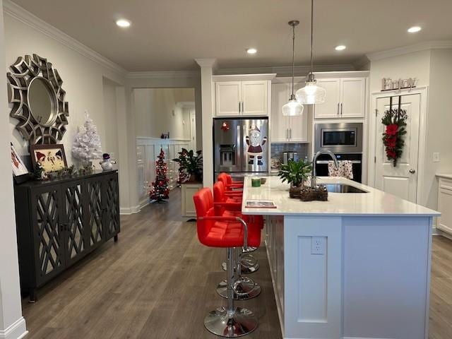 kitchen featuring a center island with sink, sink, decorative light fixtures, white cabinetry, and stainless steel appliances