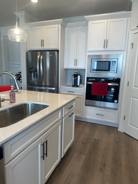 kitchen with dark wood-type flooring, a sink, white cabinetry, light countertops, and appliances with stainless steel finishes