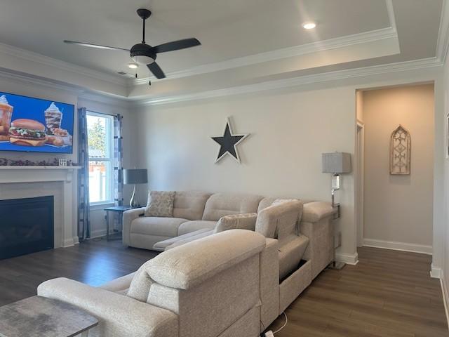 living room featuring ornamental molding, wood finished floors, a raised ceiling, and baseboards