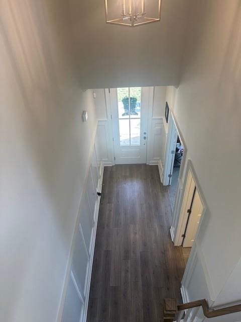 doorway to outside featuring a notable chandelier, a decorative wall, and dark wood-style flooring