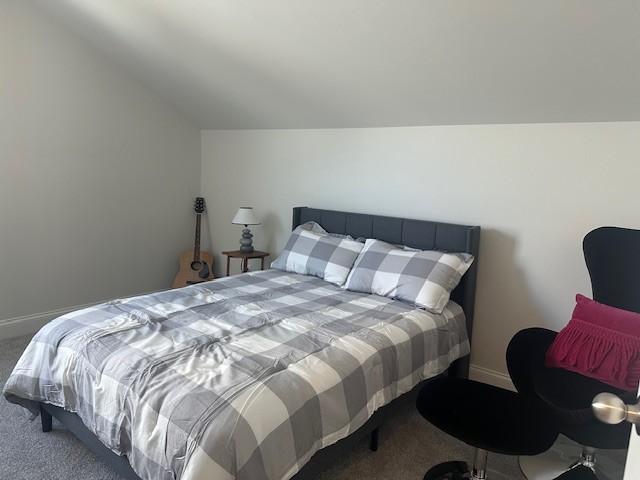 bedroom with carpet floors, baseboards, and lofted ceiling