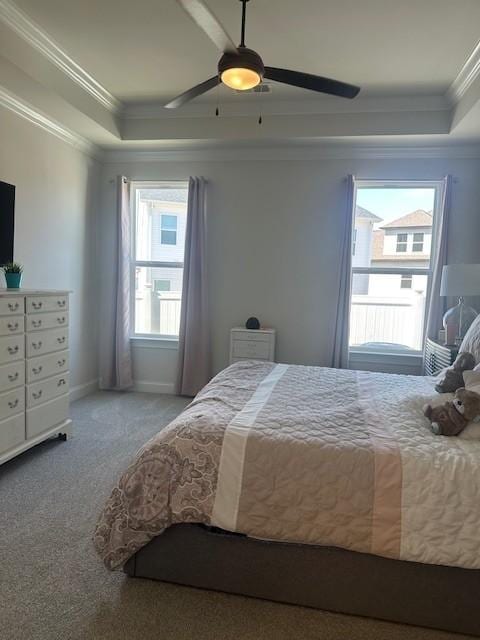 carpeted bedroom with baseboards, a tray ceiling, a ceiling fan, and ornamental molding