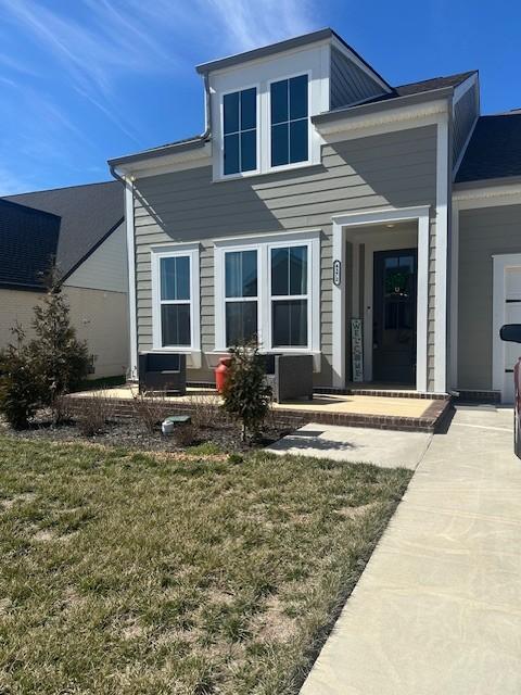 rear view of property with central air condition unit and a yard