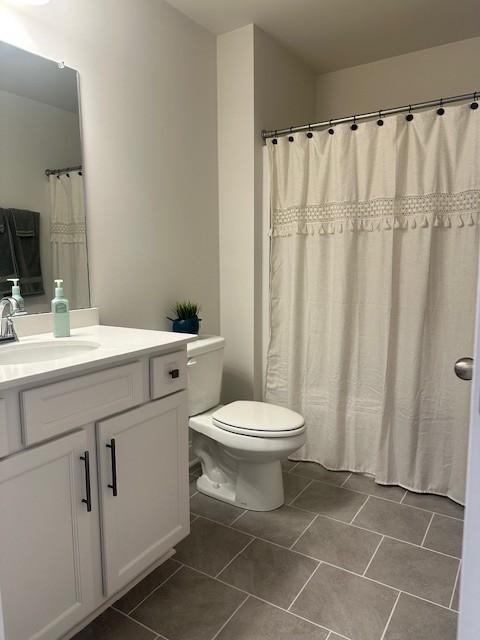 full bath with toilet, tile patterned flooring, and vanity